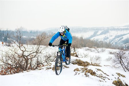 simsearch:400-09084281,k - Cyclist in Blue Riding the Mountain Bike on the Rocky Winter Hill Covered with Snow. Extreme Sport and Enduro Biking Concept. Fotografie stock - Microstock e Abbonamento, Codice: 400-09132377