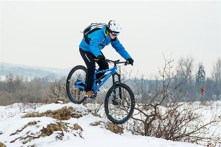 simsearch:400-09084281,k - Cyclist in Blue Riding the Mountain Bike on the Rocky Winter Hill Covered with Snow. Extreme Sport and Enduro Biking Concept. Fotografie stock - Microstock e Abbonamento, Codice: 400-09132378