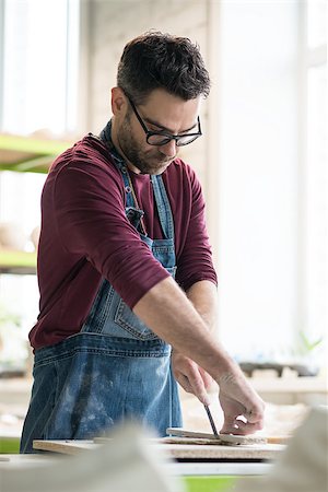 pottery sculpt - Ceramist Dressed in an Apron Cutting the Pieces of Raw Clay in the Bright Ceramic Workshop. Stock Photo - Budget Royalty-Free & Subscription, Code: 400-09132516