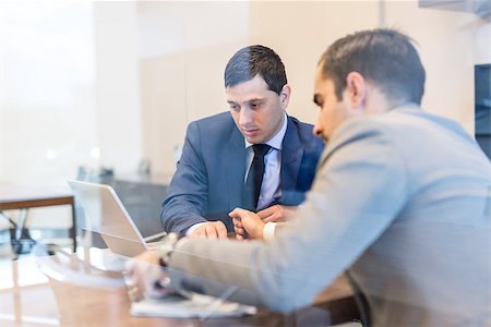 simsearch:400-09136929,k - Through the window view of two young businessmen using laptop computer at business meeting in corporative office. Photographie de stock - Aubaine LD & Abonnement, Code: 400-09170846