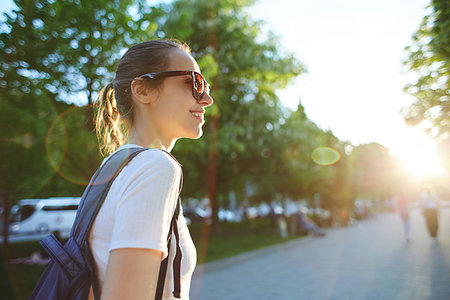 back view of a young attractive woman in white t-shirt with small city backpack at sunset on the walkway in park Stock Photo - Budget Royalty-Free & Subscription, Code: 400-09224987