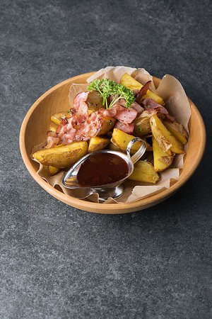 Fried potatoes with appetizing bacon and sauce are in a wooden plate. Foto de stock - Super Valor sin royalties y Suscripción, Código: 400-09225242