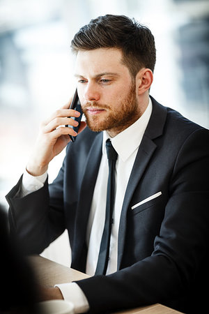 simsearch:400-04180586,k - Young businessman at the office sitting at his desk and talking on a phone Stockbilder - Microstock & Abonnement, Bildnummer: 400-09225387