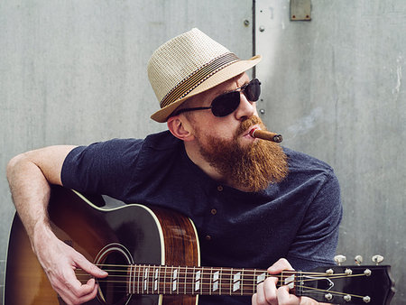 simsearch:400-04921650,k - Photo of a bearded man playing acoustic guitar white smoking a cigar. Stock Photo - Budget Royalty-Free & Subscription, Code: 400-09225514