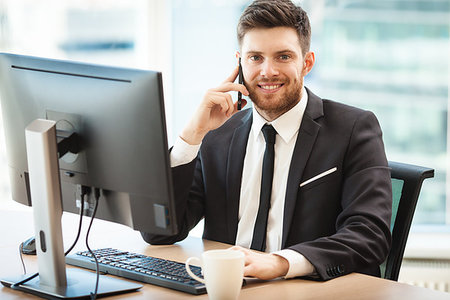 simsearch:400-04180586,k - Young businessman at the office sitting at his desk and talking on a phone Stockbilder - Microstock & Abonnement, Bildnummer: 400-09225830