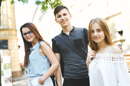 three happy friends students perfectly spend time together on a walk on the street. Focus on the boy. Stock Photo - Budget Royalty-Free & Subscription, Code: 400-09225997