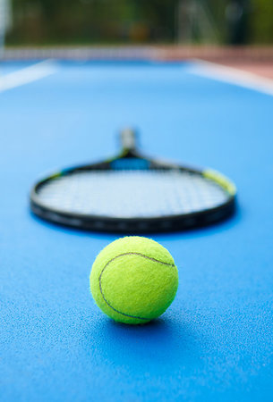 Yellow ball is laying on professional tennis racket background. A ball is on blue bright tennis cort carpet. Photo made in contrast saturated colors. Concept of sport equipment photo. Stock Photo - Budget Royalty-Free & Subscription, Code: 400-09221991