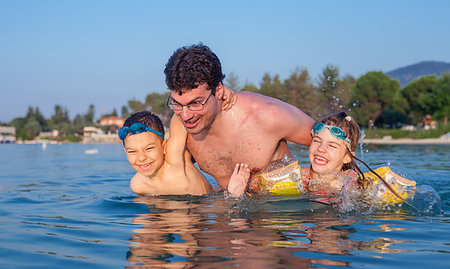 father daughter water splashing - Young father having fun in sea waters during vacation in a hot summer day with his son and daughter. Stock Photo - Budget Royalty-Free & Subscription, Code: 400-09222138