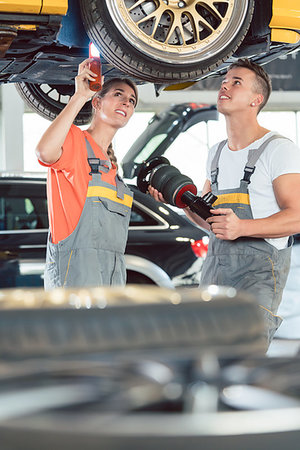 female mechanic - Experienced female auto mechanic checking tires before installing together with her colleague a new air suspension system in a modern automobile repair shop Foto de stock - Super Valor sin royalties y Suscripción, Código: 400-09222451