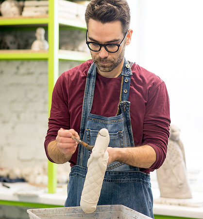 pottery sculpt - Portrait of Ceramist Dressed in an Apron Working on Clay Sculpture in the Bright Ceramic Workshop. Stock Photo - Budget Royalty-Free & Subscription, Code: 400-09222545