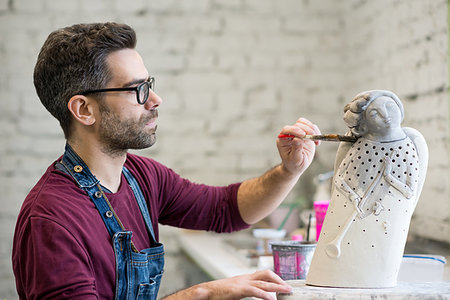 pottery sculpt - Portrait of Ceramist Dressed in an Apron Working on Clay Sculpture in the Bright Ceramic Workshop. Stock Photo - Budget Royalty-Free & Subscription, Code: 400-09222541