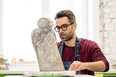 pottery sculpt - Portrait of Ceramist Dressed in an Apron Working on Clay Sculpture in the Bright Ceramic Workshop. Stock Photo - Budget Royalty-Free & Subscription, Code: 400-09222542