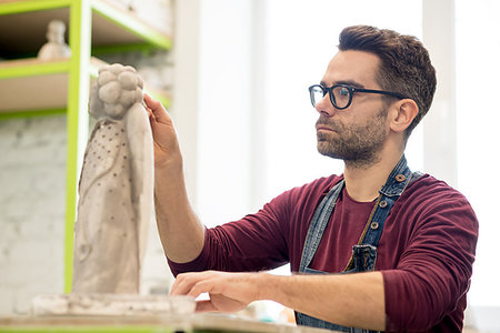 pottery sculpt - Portrait of Ceramist Dressed in an Apron Working on Clay Sculpture in the Bright Ceramic Workshop. Stock Photo - Budget Royalty-Free & Subscription, Code: 400-09222543