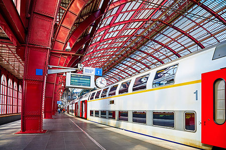 Antwerp, Belgium. Central indoor railway station. Platform made of red metal constructions with clock and panel with departure or arrival schedule. Modern double decker high-speed train Stock Photo - Budget Royalty-Free & Subscription, Code: 400-09222633