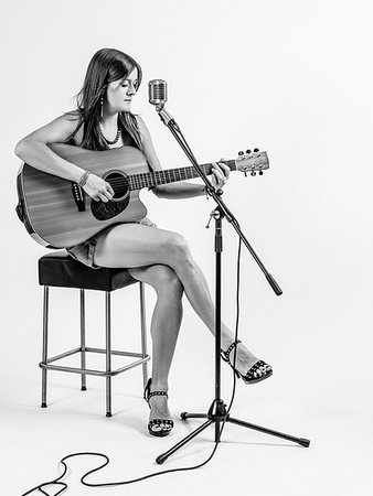 Photo of a young woman with long hair sitting on a stool playing an acoustic guitar over white background. Stock Photo - Budget Royalty-Free & Subscription, Code: 400-09223012