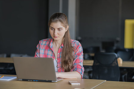 Portrait of a Serious Woman Working on Laptop in her Workplace. Foto de stock - Super Valor sin royalties y Suscripción, Código: 400-09223186
