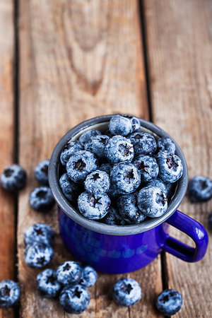 simsearch:400-08672192,k - Fresh ripe blueberries and in blue enamel mug on rustic background Photographie de stock - Aubaine LD & Abonnement, Code: 400-09223200