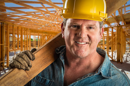 Smiling Contractor in Hard Hat Holding Plank of Wood At Construction Site. Stock Photo - Budget Royalty-Free & Subscription, Code: 400-09223487