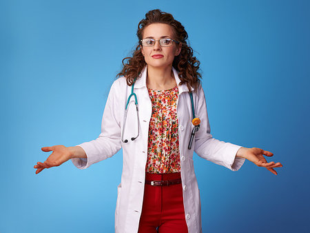 someone shrugging their shoulders - paediatrist doctor in white medical robe shrugging shoulders on blue background Stock Photo - Budget Royalty-Free & Subscription, Code: 400-09223792