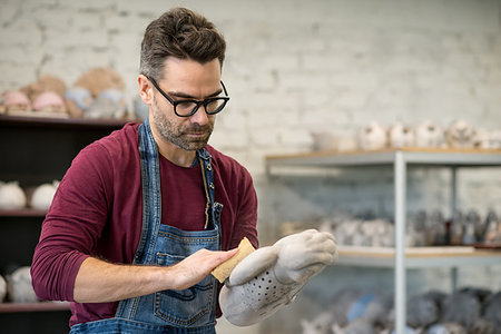 pottery sculpt - Portrait of Ceramist Dressed in an Apron Working on Clay Sculpture in the Bright Ceramic Workshop. Stock Photo - Budget Royalty-Free & Subscription, Code: 400-09237519