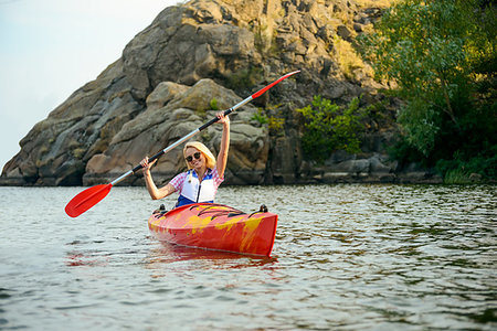 simsearch:400-09237528,k - Young Woman Paddling Kayak on the Beautiful River or Lake among Stones at the Evening Photographie de stock - Aubaine LD & Abonnement, Code: 400-09237566