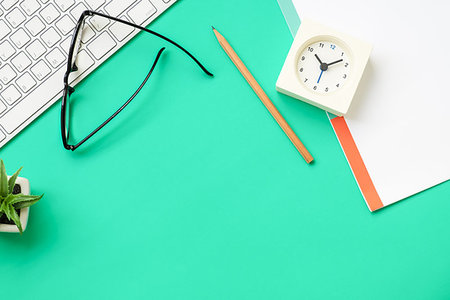 Top view of office desk - keyboard, clock, pencil, paper, eyeglasses on modern fresh green table Stock Photo - Budget Royalty-Free & Subscription, Code: 400-09237668