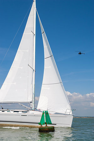 simsearch:400-09237900,k - Sailing boat, sail boat or yacht with white sails passing a green navigation buoy at sea while a black helicopter flies over head Foto de stock - Super Valor sin royalties y Suscripción, Código: 400-09237900