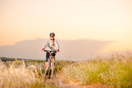 simsearch:400-06922980,k - Young Woman Riding the Mountain Bikes in the Beautiful Field Full of Feather Grass at Sunset. Adventure and Travel Concept. Stock Photo - Budget Royalty-Free & Subscription, Code: 400-09237994