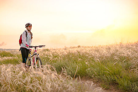 simsearch:400-06922980,k - Young Woman Riding the Mountain Bikes in the Beautiful Field Full of Feather Grass at Sunset. Adventure and Travel Concept. Stock Photo - Budget Royalty-Free & Subscription, Code: 400-09237995