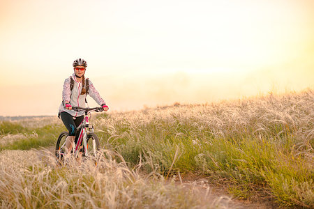 simsearch:400-06922980,k - Young Woman Riding the Mountain Bikes in the Beautiful Field Full of Feather Grass at Sunset. Adventure and Travel Concept. Stock Photo - Budget Royalty-Free & Subscription, Code: 400-09237997