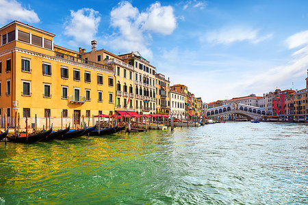 Venice, Italy. Panorama view at Rialto Bridge on Grand Canal in Venezia. Gondolas floating by piers docksamong antique buildings and traditional italian Venetian architecture. Sunny day with blue sky and clouds. Stock Photo - Budget Royalty-Free & Subscription, Code: 400-09238284