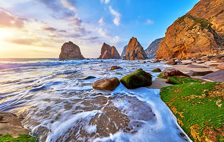 Portugal Ursa Beach at atlantic coast of Atlantic Ocean with rocks and sunset sun waves and foam at sand of coastline picturesque landscape panorama. Stones with green moss in front. Stock Photo - Budget Royalty-Free & Subscription, Code: 400-09238363