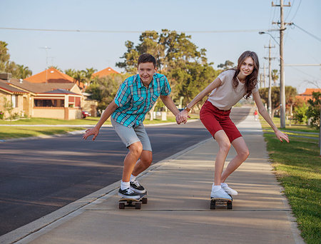 Happy brother and sister having fun with  skateboard on the street in the evening light Stock Photo - Budget Royalty-Free & Subscription, Code: 400-09274503