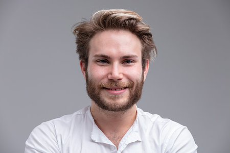 Studio shot close-up portrait of a handsome blond bearded young man smiling happy against beige background for copy space Stock Photo - Budget Royalty-Free & Subscription, Code: 400-09273558