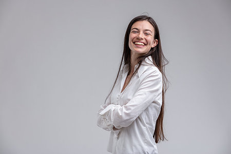 Portrait of long-haired brunette smiling woman standing with arms crossed Stock Photo - Budget Royalty-Free & Subscription, Code: 400-09273552