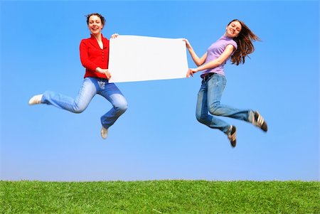 Girls jumping with blank sheet against blue sky Stock Photo - Budget Royalty-Free & Subscription, Code: 400-03914170