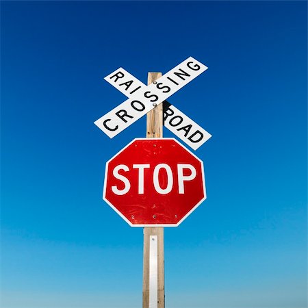 passagem de nível - Railroad crossing and stop signs against blue sky. Foto de stock - Royalty-Free Super Valor e Assinatura, Número: 400-03924053