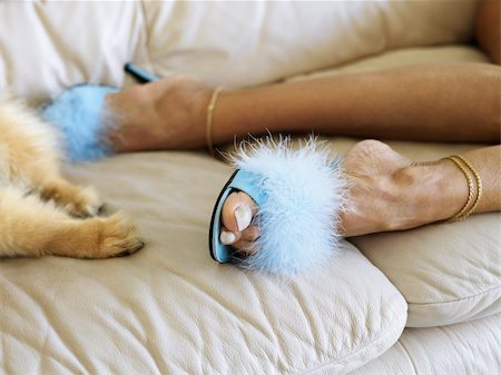 Feet shot of Caucasion middle-aged woman wearing furry heels beside dog paws both lying on couch. Stock Photo - Budget Royalty-Free & Subscription, Code: 400-03924081