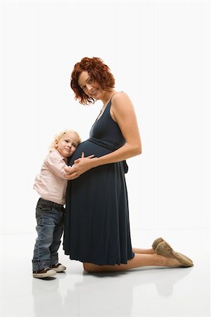 Caucasion mid-adult attractive pregnant woman kneeling in front of female toddler who is pressing ear against belly. Stock Photo - Budget Royalty-Free & Subscription, Code: 400-03924205