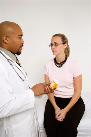 simsearch:400-04449853,k - Mid-adult African-American doctor explaining medication to Caucasion mid-adult female patient. Photographie de stock - Aubaine LD & Abonnement, Code: 400-03924284