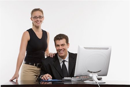 simsearch:400-03926822,k - Caucasian mid-adult woman touching shoulder of man sitting at computer and looking at viewer. Stock Photo - Budget Royalty-Free & Subscription, Code: 400-03924452