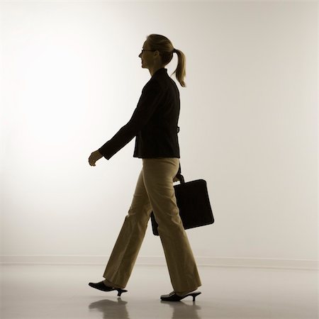 Silhouette of mid-adult Caucasian businesswoman walking and carrying briefcase. Stock Photo - Budget Royalty-Free & Subscription, Code: 400-03924470
