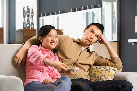 Asian couple sitting on couch watching TV. Stock Photo - Budget Royalty-Free & Subscription, Code: 400-03924680