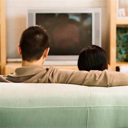 Asian couple sitting on couch watching TV. Stock Photo - Budget Royalty-Free & Subscription, Code: 400-03924681