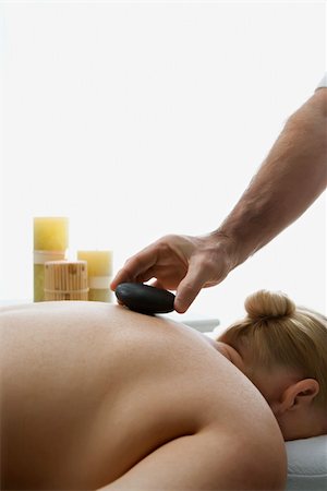 simsearch:400-04956215,k - Caucasian middle-aged male massage therapist placing hot stone on back of Caucasian middle-aged woman lying on massage table. Photographie de stock - Aubaine LD & Abonnement, Code: 400-03925695