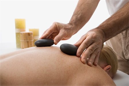 simsearch:400-04956215,k - Caucasian middle-aged male massage therapist placing hot stones on back of Caucasian middle-aged woman lying on massage table. Photographie de stock - Aubaine LD & Abonnement, Code: 400-03925696