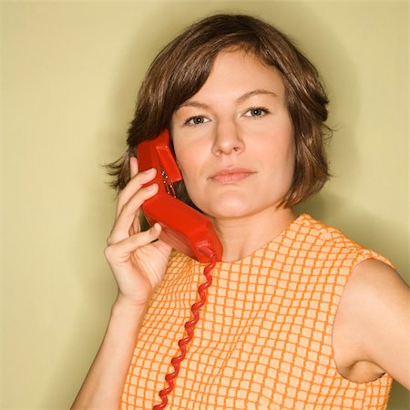 Head shot of pretty Caucasian mid-adult woman wearing orange dress listening to red telephone receiver. Stock Photo - Budget Royalty-Free & Subscription, Code: 400-03925713