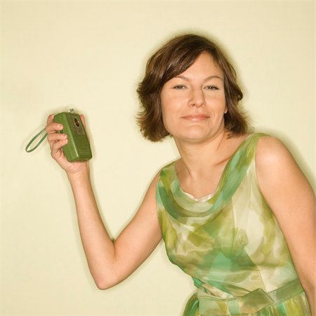 simsearch:400-04451365,k - Pretty Caucasian mid-adult woman wearing green vintage dress with handheld radio smiling at viewer. Foto de stock - Super Valor sin royalties y Suscripción, Código: 400-03925731