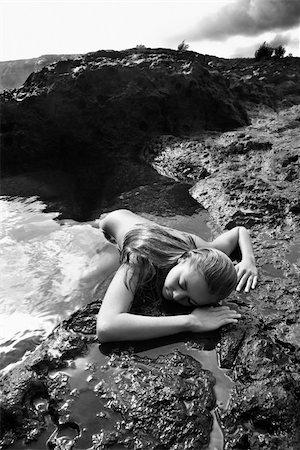 simsearch:400-03940673,k - Young nude Asian woman partially submerged in water lying face down on rocky coast. Stock Photo - Budget Royalty-Free & Subscription, Code: 400-03925899