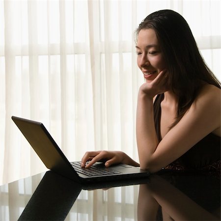 simsearch:400-03926201,k - Taiwanese mid adult woman on laptop smiling. Fotografie stock - Microstock e Abbonamento, Codice: 400-03926204